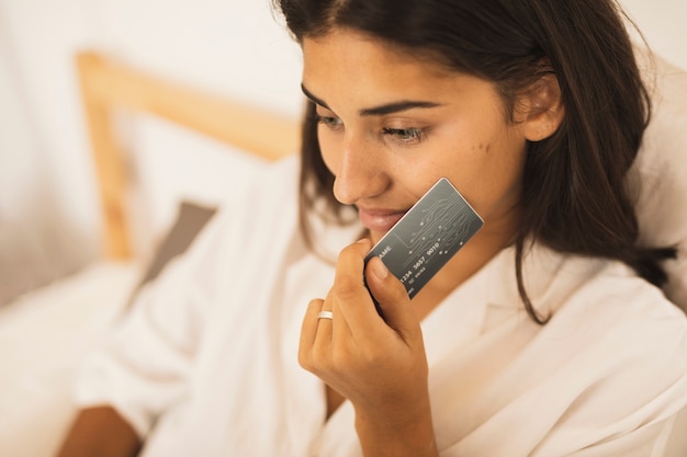 Woman holding a credit card next to her cheek